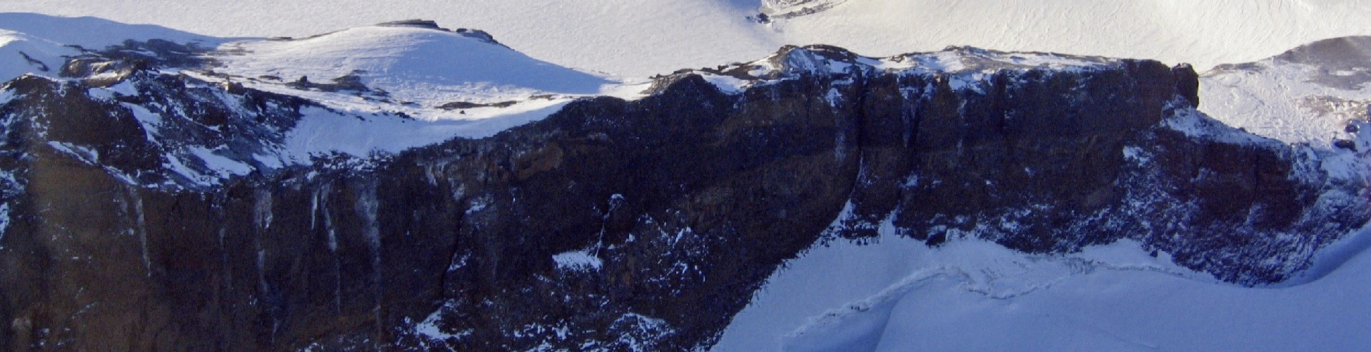 View of Turtle Rock (2006). A view from above of a rocky cliff face in the snow.